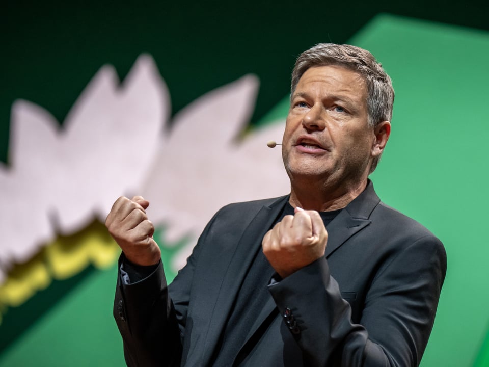 Habeck de terno e microfone gesticula no palco.