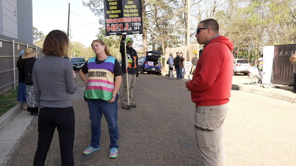 The reporter is interviewing a woman, abortionists on the back and right.