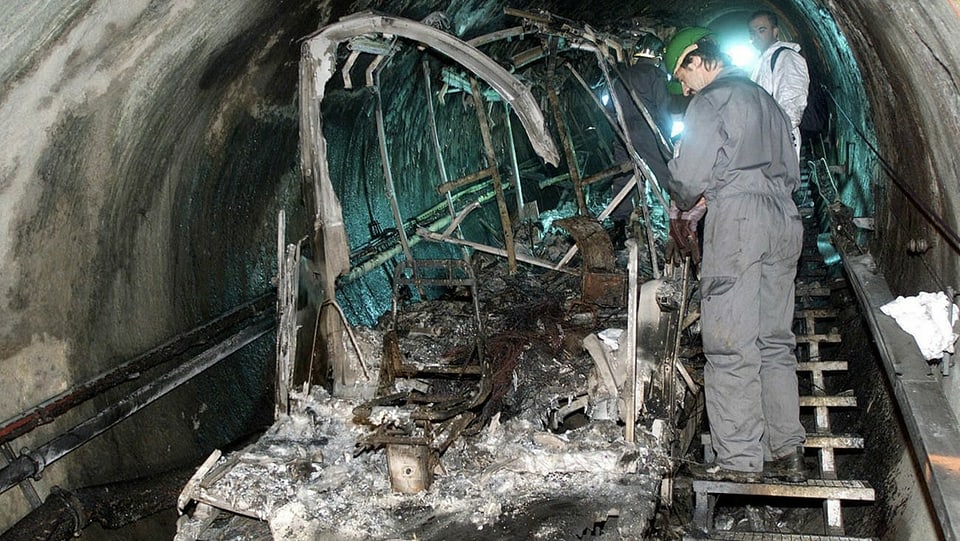 Mitglieder der Bergungsmannschaft betrachten den ausgebrannten Zug vier Tage nach der Katastrophe.