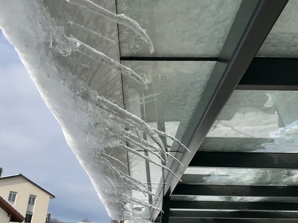 Uetendorf/BE Eiszapfen an Schnee, der von einem Glasdach rutscht.
