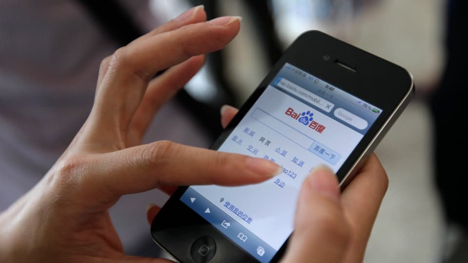 Eine Hand tippt einen Suchbegriff in die mobile Suchmaschine von Baidu.
