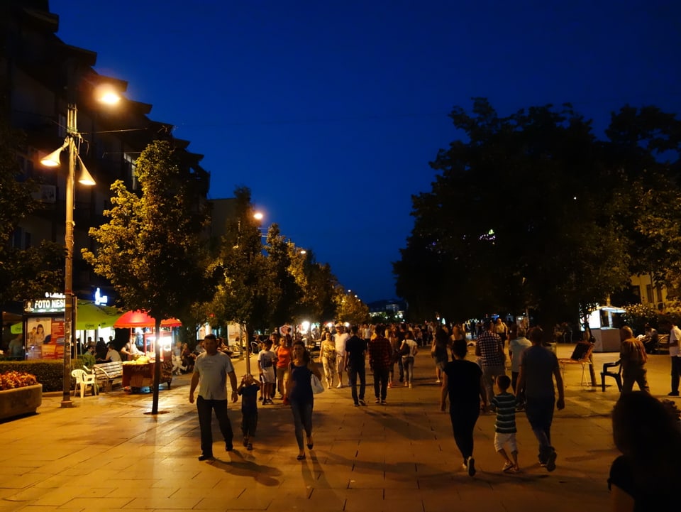 Menschen flanieren am Abend auf dem grossen Boulevard in Pristina.