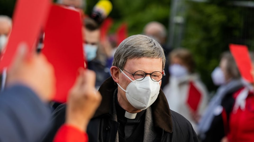 Kardinal Rainer Maria Woelki, Erzbischof von Köln, geht durch einen Spalier aus Gemeindemitgliedern, die ihm vor der Kirche St. Maria vom Frieden die Rote Karte zeigen.