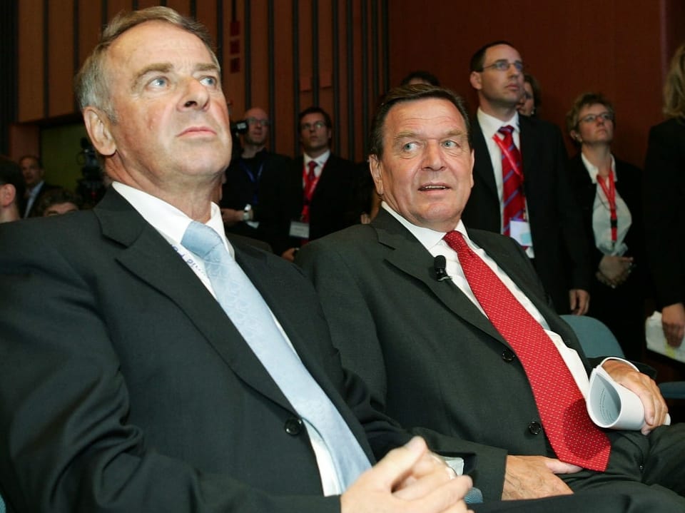 Gerhard Schröder sitzt neben Adolf Ogi im Publikum.