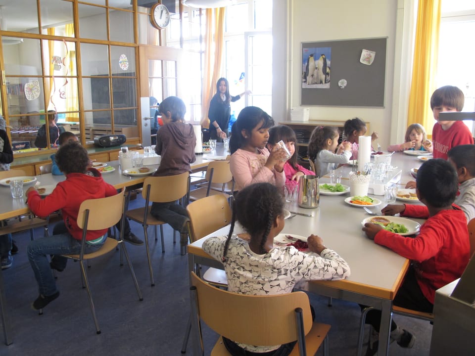 Kinder an Tischen mit vollen Tellern vor sich