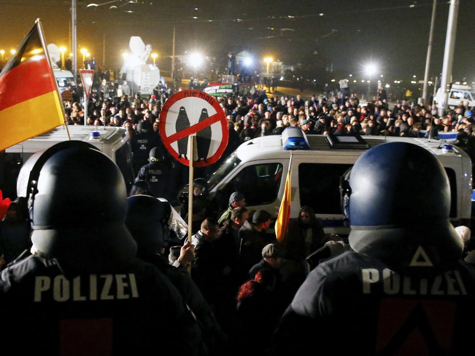 Polizisten mit Schutzhelmen sichern die Pegida-Demonstration in Dresden ab. 
