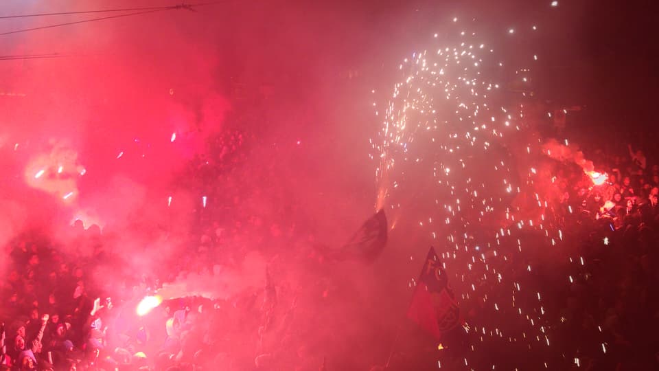Rote Pyros und Feuerwerk über einer Menschenmenge