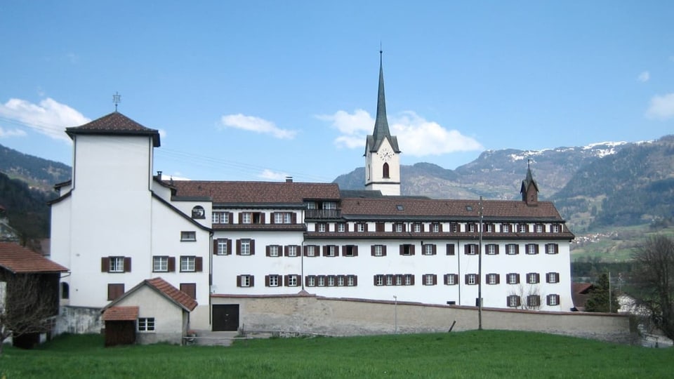 Ein weisses Kloster in einer Bergwelt.