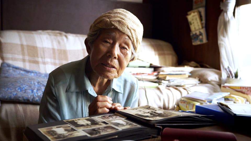 Eine late japanische Frau blättert in einem Fotoalbum.