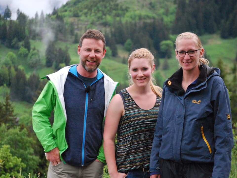 Nik posiert mit zwei jungen Frauen, die die Alp bewirtschaften. 