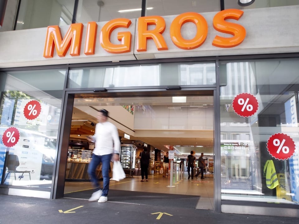 Über einem Eingang prangt das Migros-Logo. Am Schaufenster hat es rote Rabatt-Sticker.