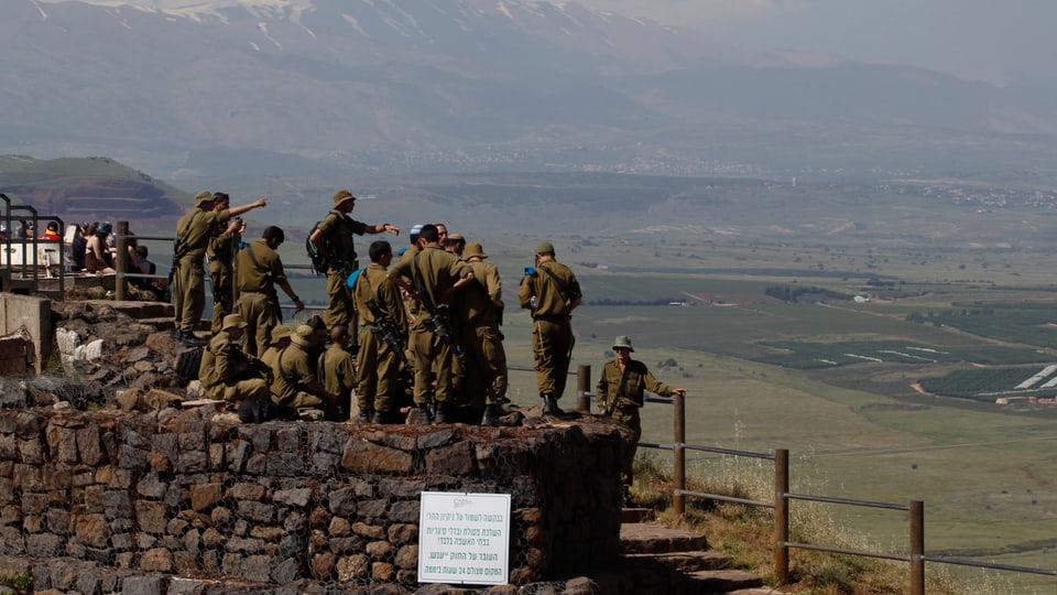 Israelische Soldaten stehen auf einem Hügel und werden gebrieft. 