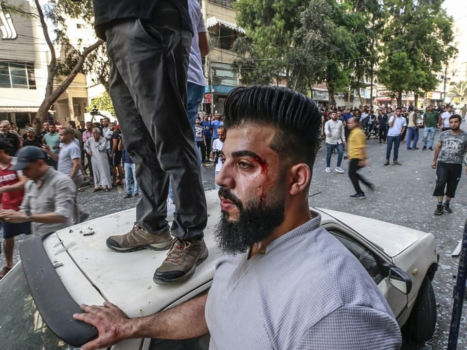 Ein verletzter Palästinenser steht am Ort, der von israelischen Angriffen getroffen wurde. 