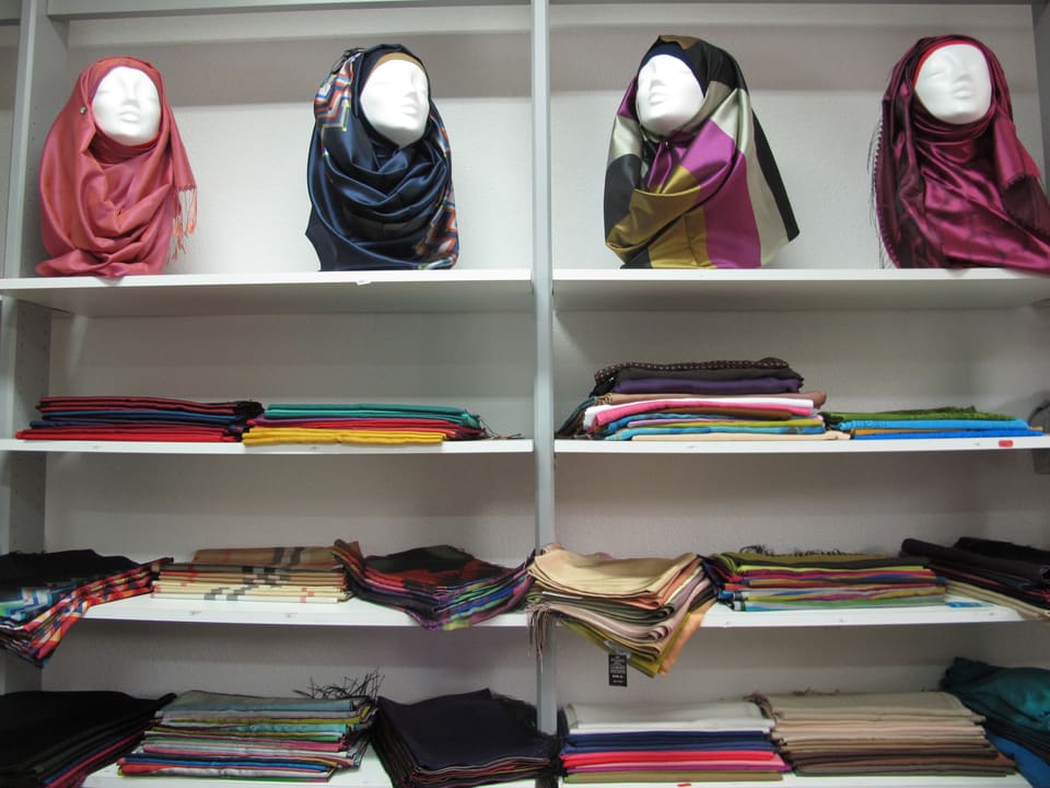 Ein Wandregal voll mit Kopftüchern - sogenannten Hijabs - in allen Farben und Mustern.
