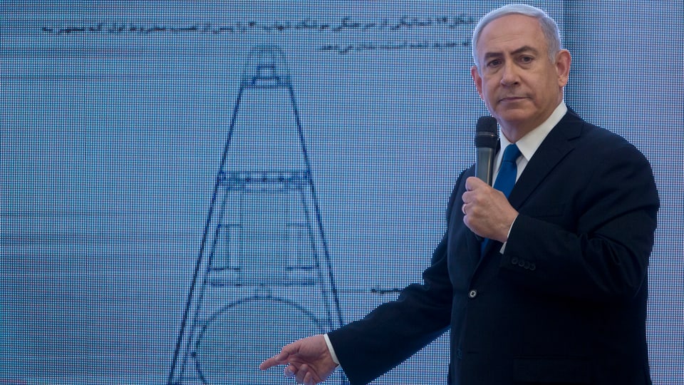 Netanjahu mit Mikrofon vor einer Grafik, auf die er zeigt.