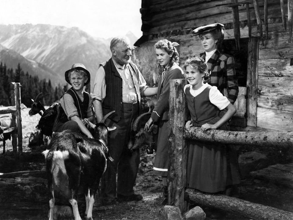 Der Ziegenpeter mit einer Ziege, der Almöhi, Klara, Heidi und Fräulein Rottenmeier stehen vor der Alphütte und schauen ins Tal.