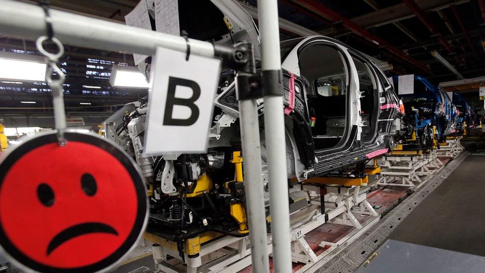 Ein trauriges Smilie-Symbol vor einem Autobau-Förderband.