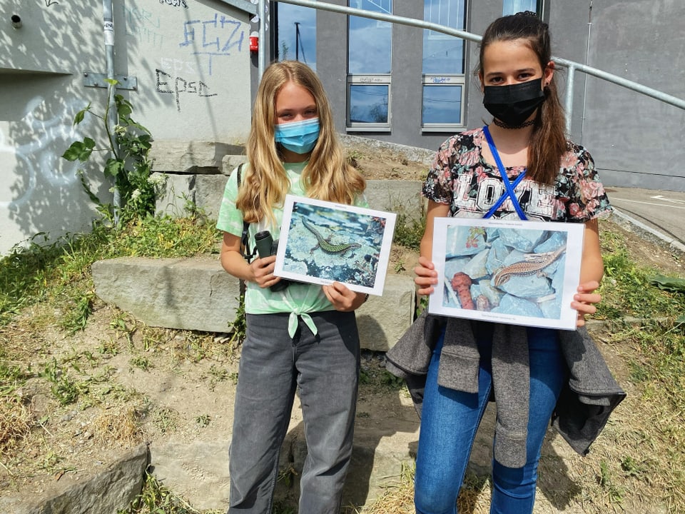 Leanne und Joëlle halten ein Foto von Eidechsen in die Kamera