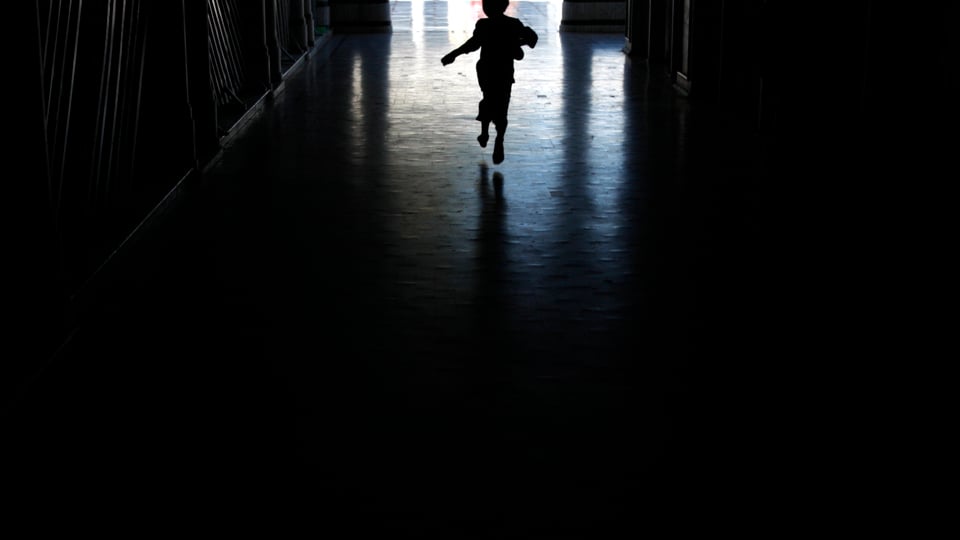 Kleiner Junge rennt in dunklem Gang