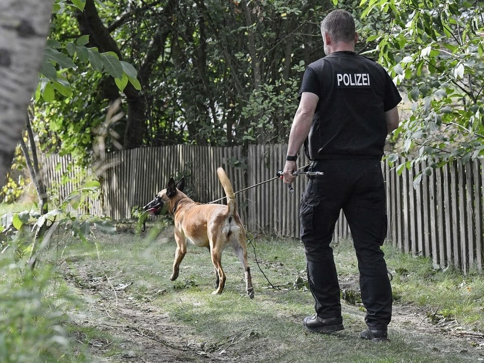 Ein Polizist mit Spürhund auf einem Gartengelände in Hannover