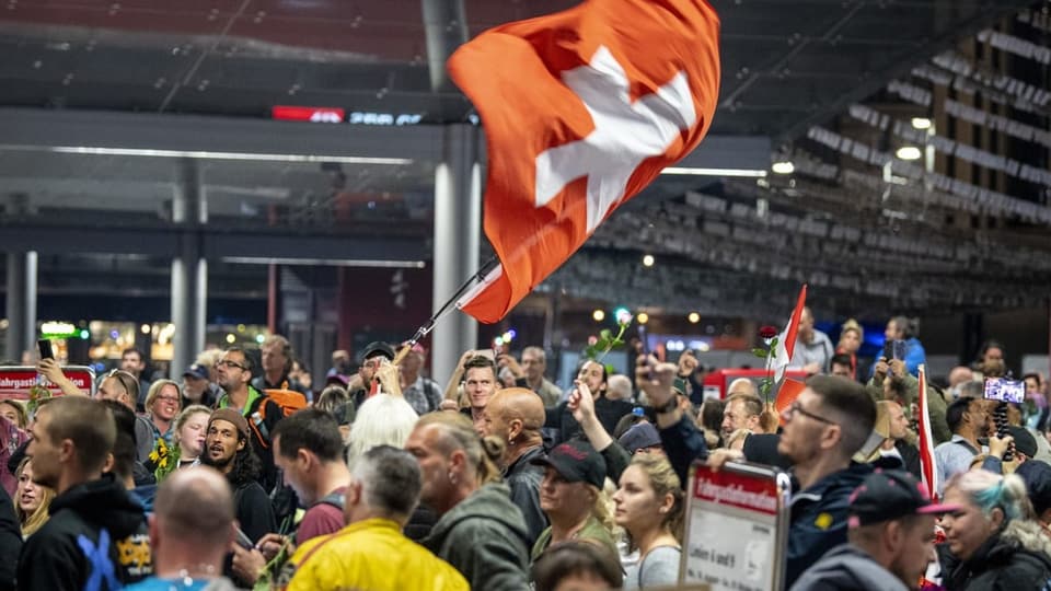 Eine Masse von Menschen, in der Mitte weht eine grosse Schweizerflagge.