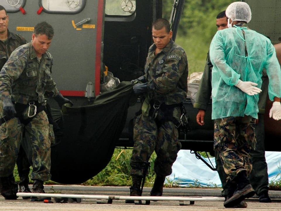 Soldaten tragen einen Leichensack.