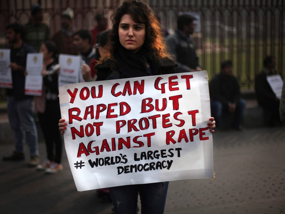Eine junge Frau hält ein Plakat mit der Aufschrift: «Du kannst vergewaltigt werden, aber Du darfst nicht gegen Vergewaltigungen demonstrieren. In der grössten Demokratie der Welt.»