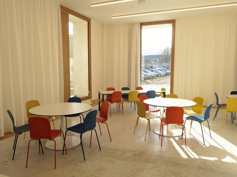 In einem hellen Raum stehen moderne Tische und Stühle. 
