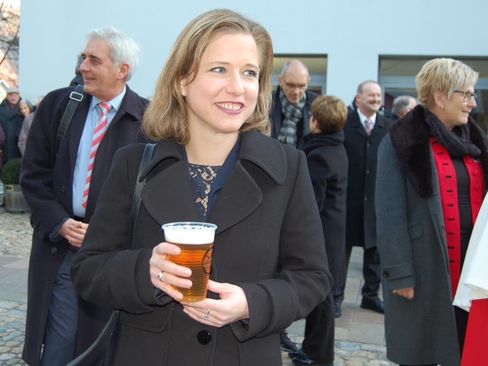 Die Politikerin hat ein Bier in der Hand.