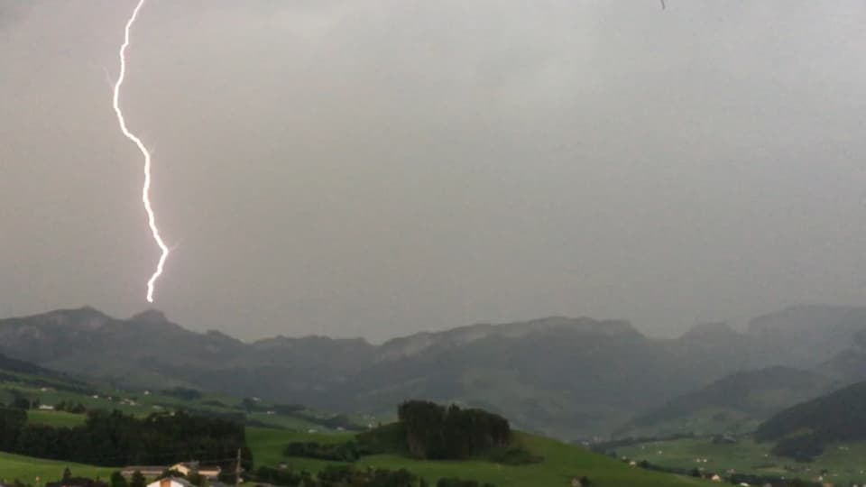 Ein graues Bild aus dem Appenzeller Mittelland. Ein Blitz trifft die Spitze des weit entfernten Hohen Kastens.