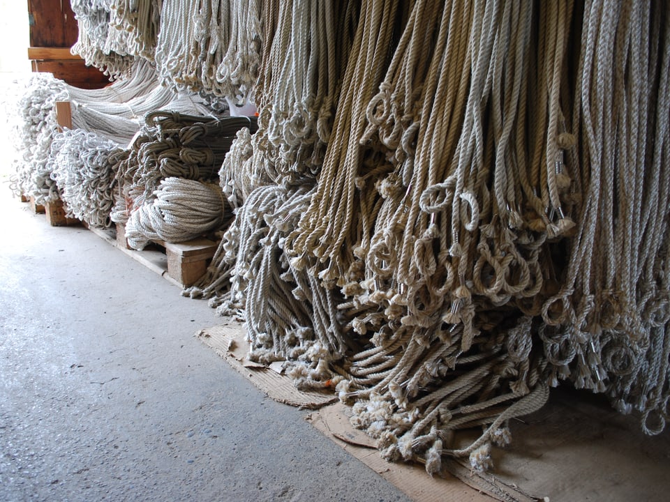 Ganz viele verschiedene Seile hängen an einer Wand. 