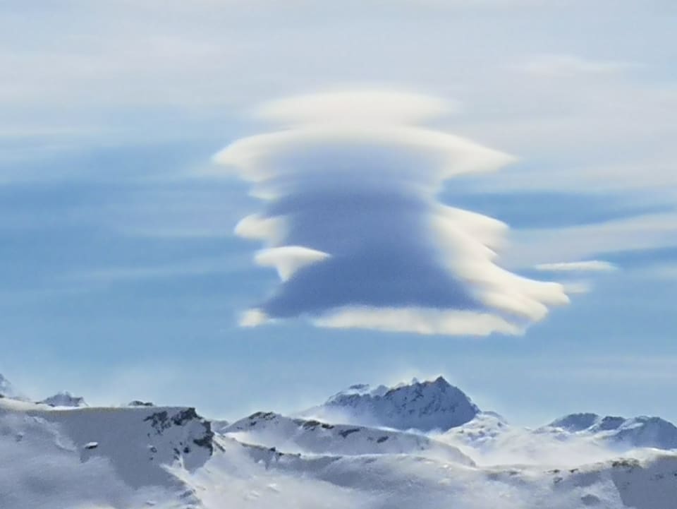 Föhnwolken stehen über dem  tiefwinterlichen Alpen.