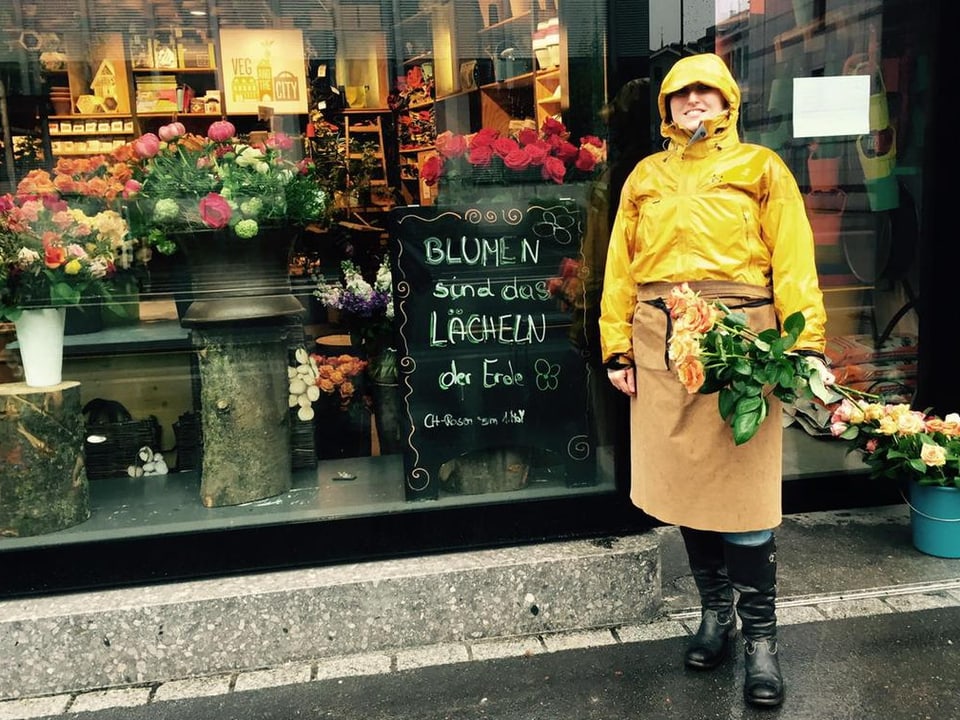 Eine Verkäuferin in gelber Pellerine verteilt Rosen vor ihrem Geschäft an der Europaallee.
