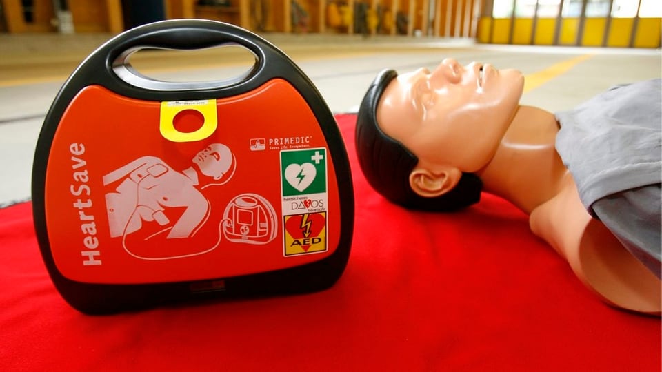 Ein Defibrillator im Vordergrund und eine Übungspuppe dahinter
