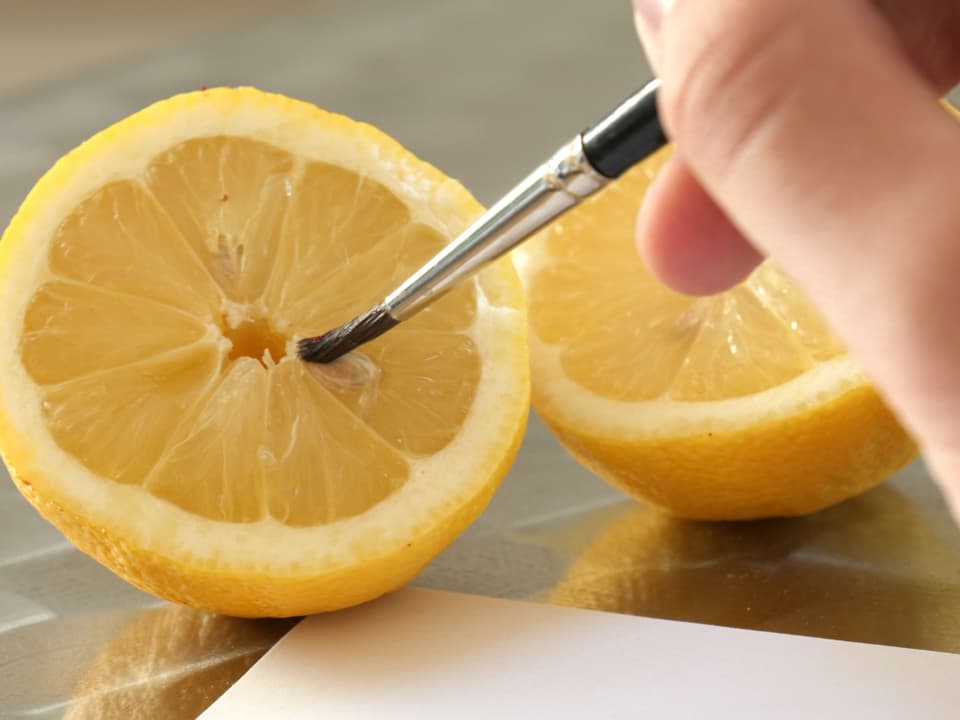 Halbiere eine Zitrone und nutze deren Flüssigkeit als Tinte. Du kannst mit deinen Fingern schreiben oder beispielsweise einen Pinsel verwenden. Schreibe nun deine Botschaft auf ein Blatt Papier.