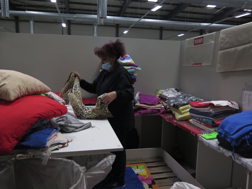 Eine Frau nimmt die gebrauchten Kleider auseinander und kontrolliert sie.