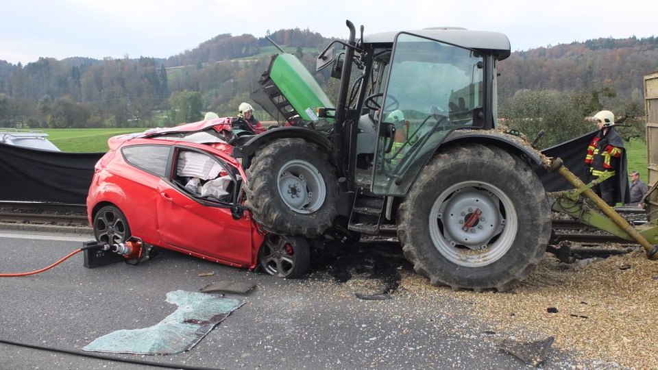 Aufnahme des zerstörten roten Autos und des demolierten grünen Traktors. 