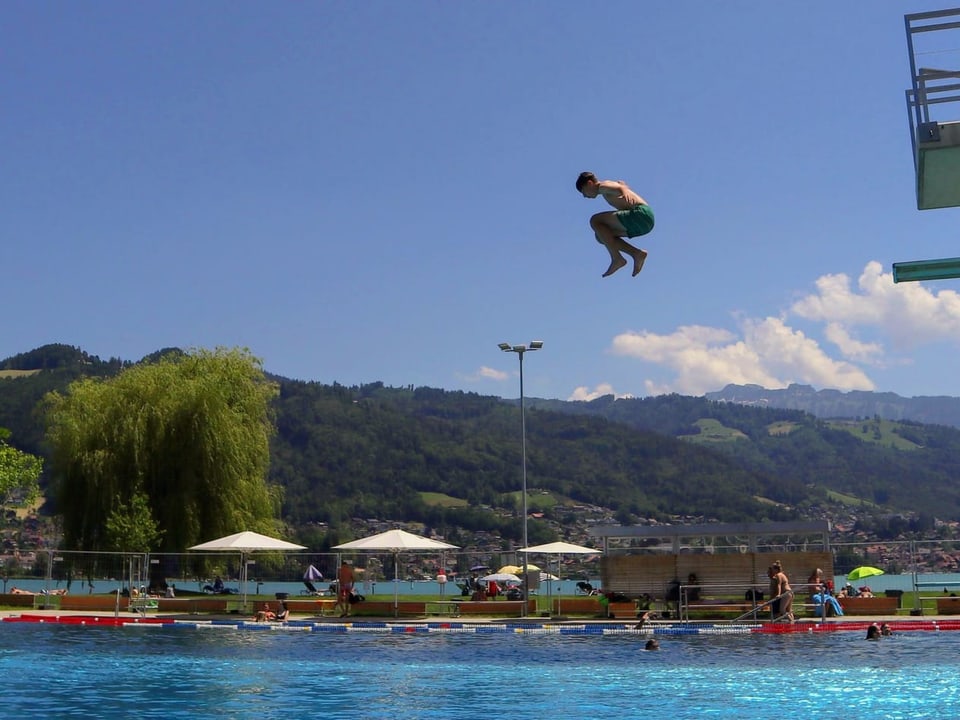 Knabe springt vom Sprungturm in einer Badi ins Wasser