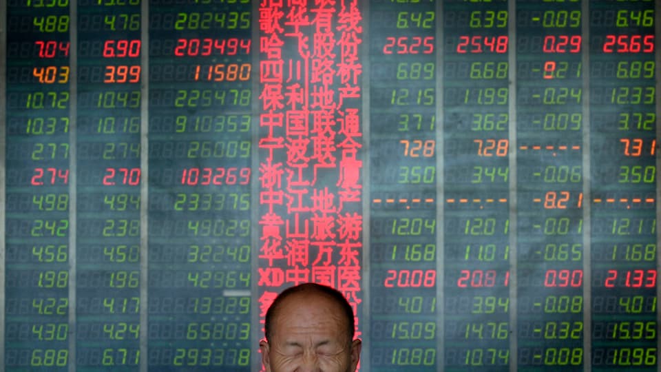 Mann mit geschlossenen Augen vor einer Tafel mit Aktienkursen.