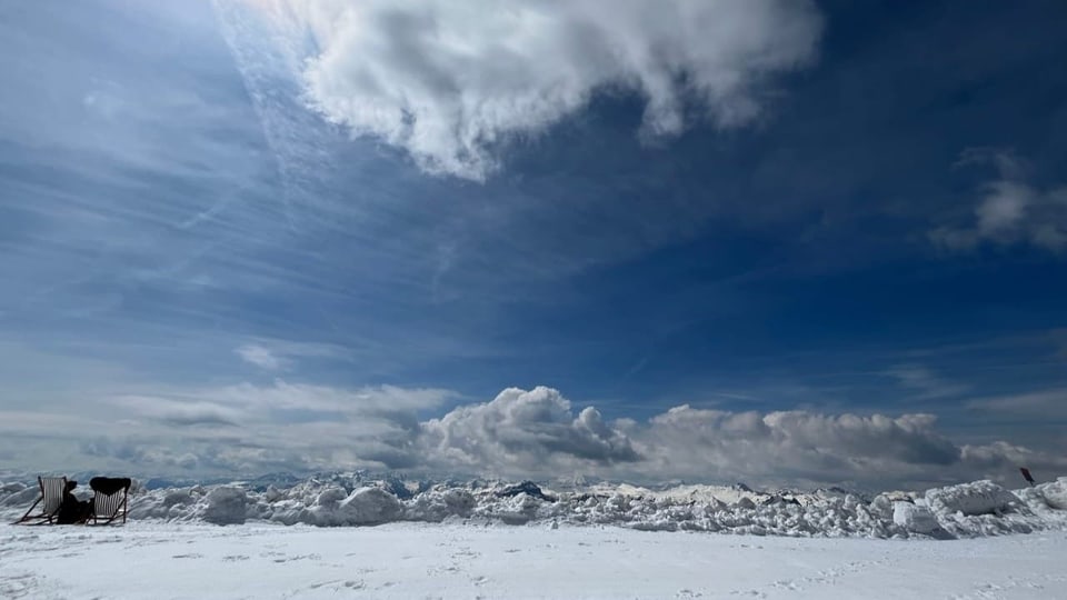 Schneelandschaft mit Liegestuhl und dramatischem Wolkenhimmel