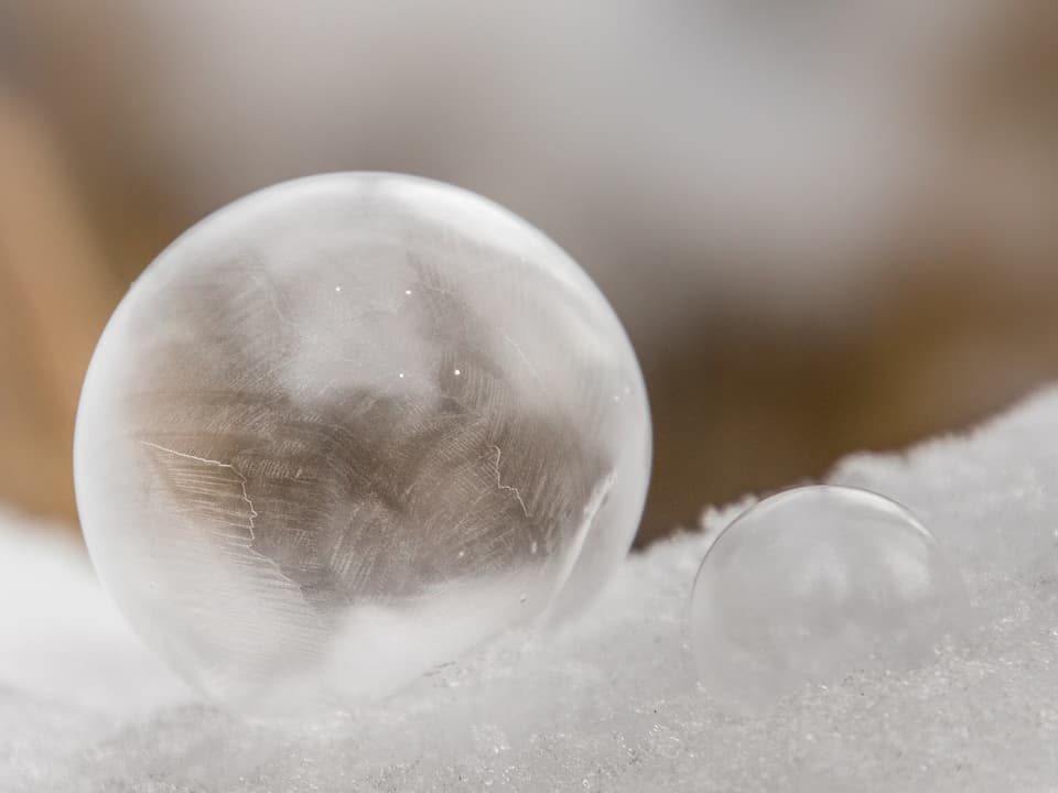 Zwei gefrorene Seifenblasen im Schnee.