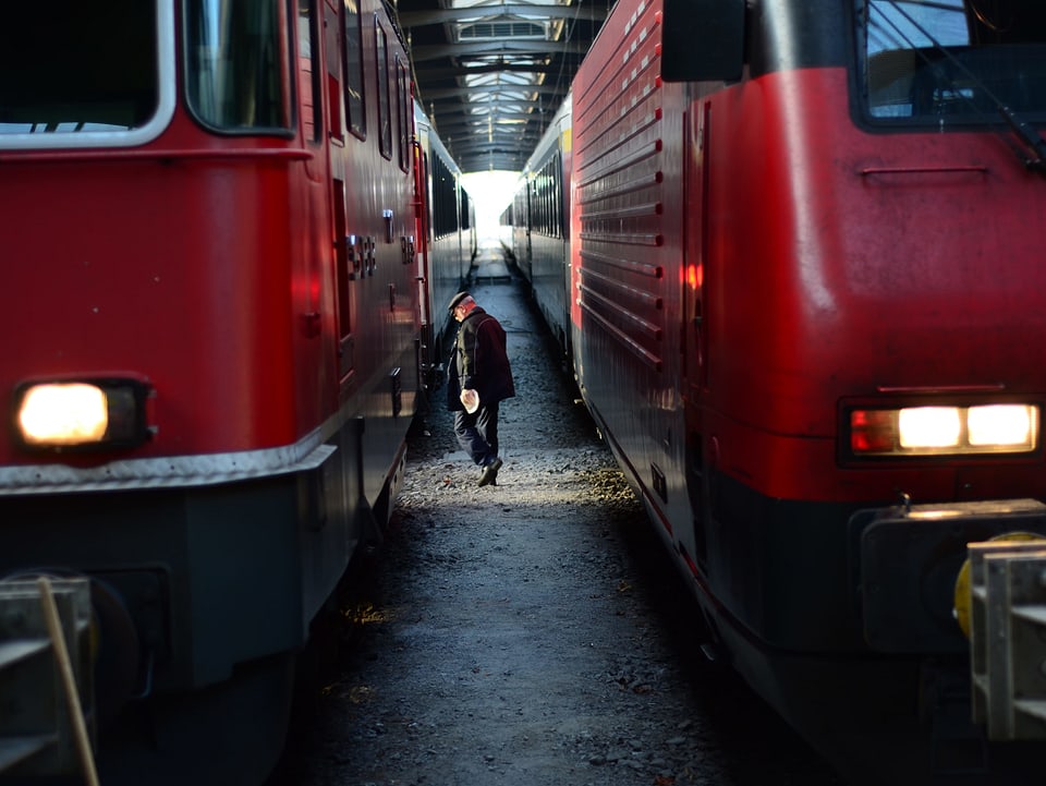 Ein SBB-Angestellter schreitet zwischen zwei roten Zügen hindurch.