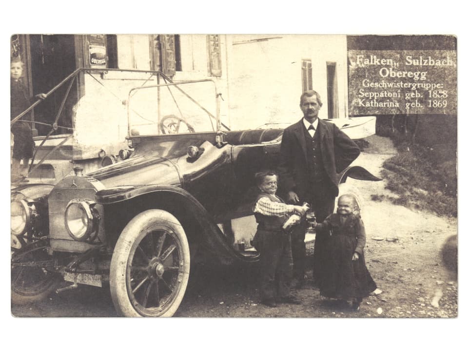 Alte Fotografie von drei Personen vor einem Auto.
