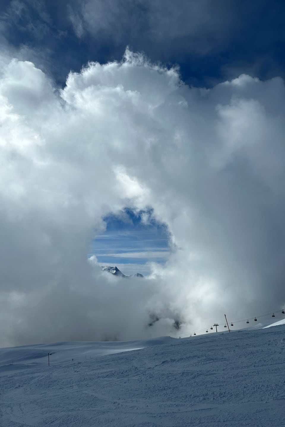  Skigebiet mit riesiger Wolke, in der ein Loch zu sehen ist.