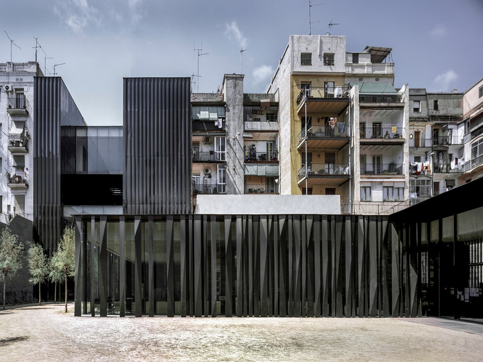 Eine Gebäude aus Glas, das mit schwarzen Säulen umhhüllt ist.
