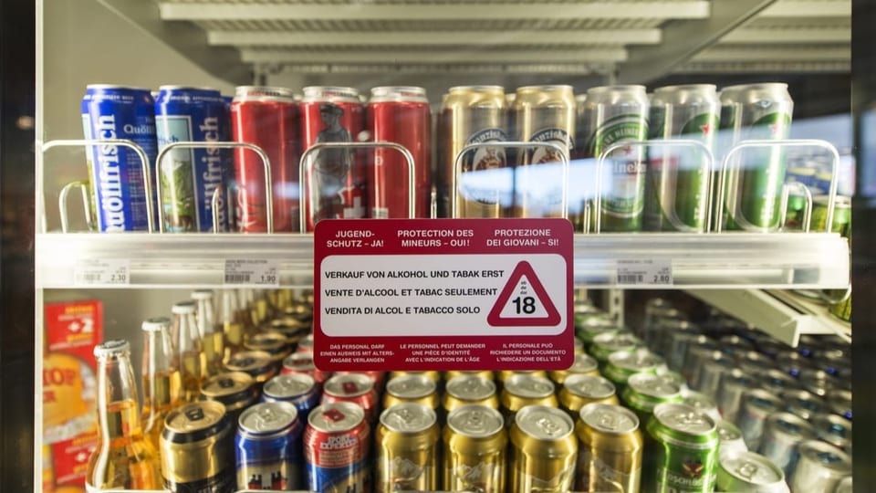 Ein Kühlschrank mit Bierdosen. Auf der Tür klebt der Hinweis, dass Alkohol und Tabak erst ab 18 Jahren verkauft wird.