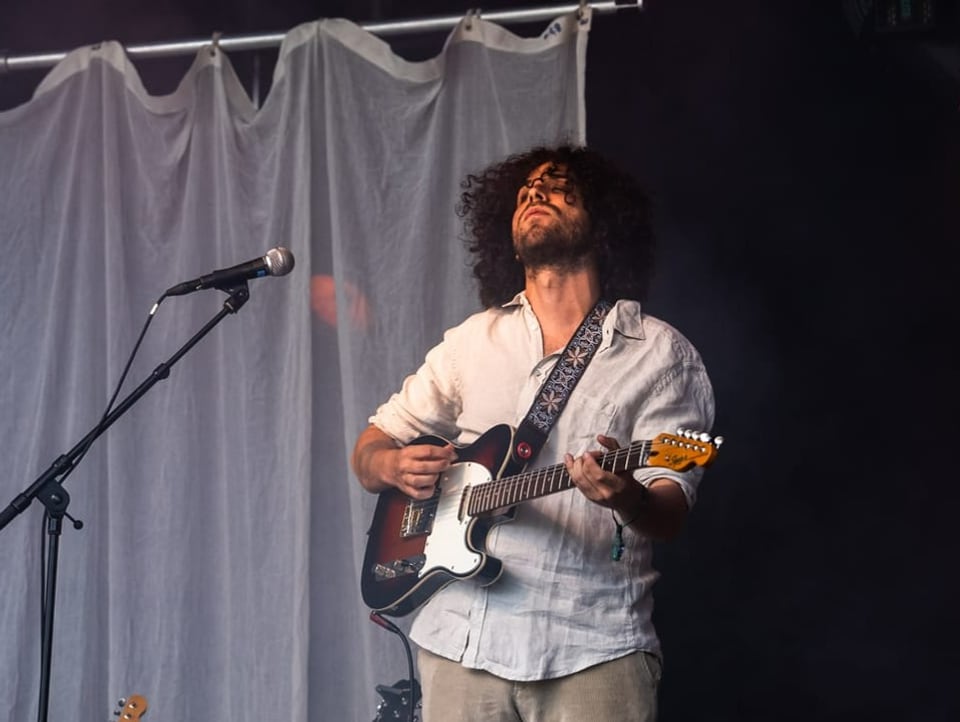 A member of Soft Loft is standing on stage holding a guitar