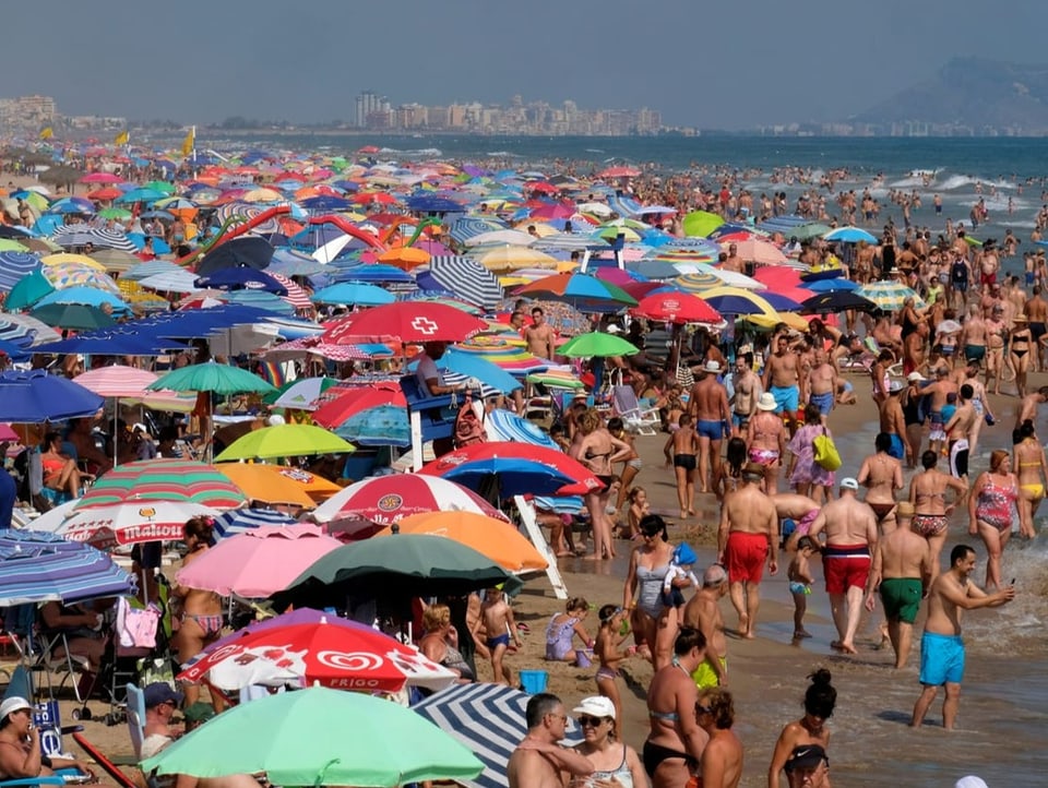 Überfüllter Strand mit vielen Sonnenschirmen