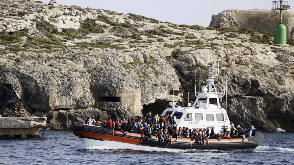 Auf einem Boot der italienischen Küstenwache befinden sich zahlreiche Migrantinnen und Migranten.