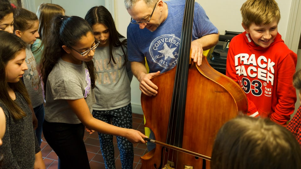 Eine Schülerin streicht zum ersten Mal ein Cello.